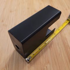 a tape dispenser sitting on top of a wooden table next to a ruler