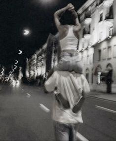 two people are walking down the street at night, one is carrying another person on his back