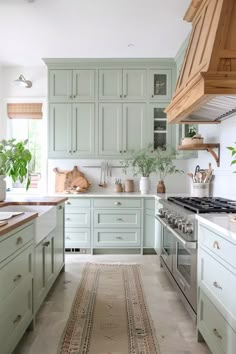 a kitchen with green cabinets and an area rug on the floor in front of the stove