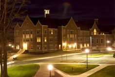 a night time view of a campus with cars parked in the parking lot and lights on