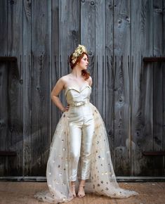 a woman is standing in front of a wooden wall wearing a white outfit with gold stars on it