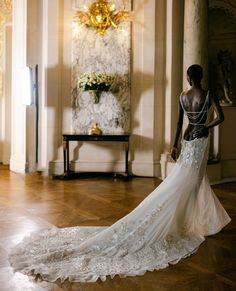 a woman in a wedding dress is looking at the chandelier on the wall