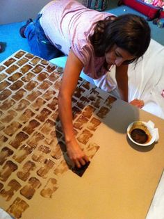 a woman is making something out of cardboard on the floor with her hands and feet