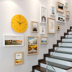 there are many framed pictures on the wall next to the stair case and clock,