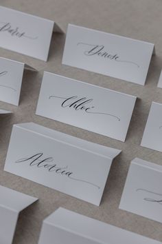 place cards with calligraphy on them sitting on a table