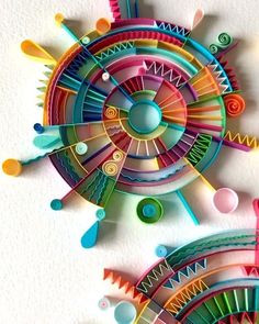 two colorful paper sculptures on a white wall next to each other with circles and shapes