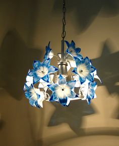 a blue and white flower chandelier hanging from a ceiling fixture in a room