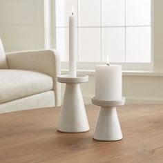 two white candles sitting on top of a wooden table