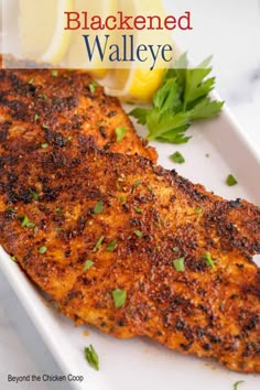 a close up of a fish on a plate with lemon wedges and parsley