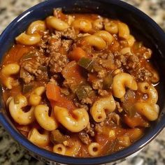 a blue bowl filled with macaroni and cheese soup on top of a counter