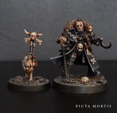 two miniature figurines with skulls on their heads and one is holding a knife