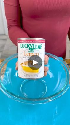 a woman holding a can of lucky leaf lemon tea on top of a blue table