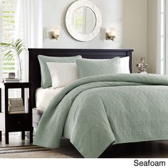 a bed with a green comforter and pillows