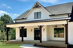 a white house with black shutters on the front porch and covered in wood beams