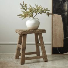 a white vase sitting on top of a wooden stool