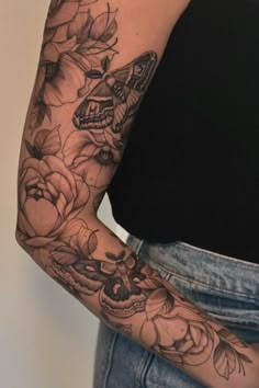 a woman's arm with flowers and a butterfly tattoo on her left arm is shown