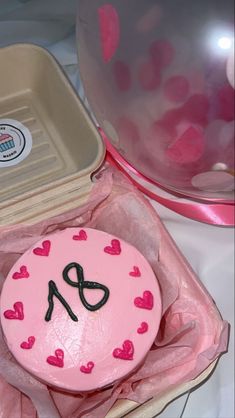 a pink cake sitting in a box on top of a table next to a bowl