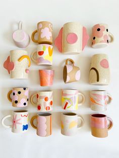 many different cups and mugs are arranged on a white surface with one cup in the middle