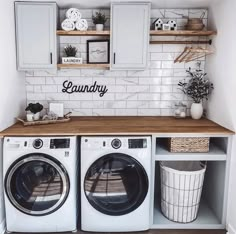 a washer and dryer in a laundry room with white cabinets, wood counter tops and shelves