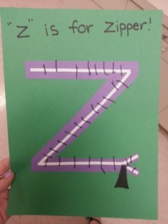 a hand holding up a piece of paper that says z is for zipper