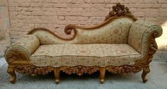 an ornate couch sitting in front of a brick wall