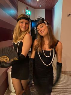 two young women dressed in flappers and garb posing for the camera with their arms around each other