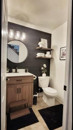 a white toilet sitting next to a wooden cabinet in a bathroom under a round mirror