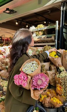 a woman holding flowers in her hands while standing next to a bunch of bags full of flowers