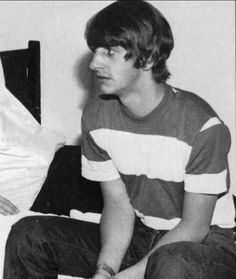 black and white photograph of young man sitting on bed