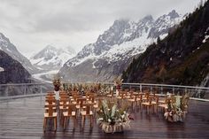 tables and chairs set up on a deck with mountains in the background