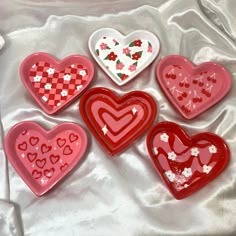 six heart shaped dishes sitting on top of a white cloth