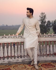 a man in a white outfit standing on a balcony