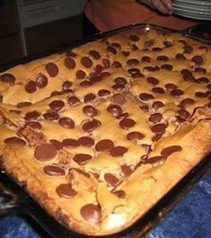 a pan filled with chocolate chip cookies on top of a blue cloth covered tablecloth