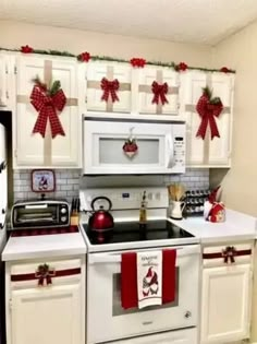 a kitchen decorated for christmas with red and white bows on the cabinets, stove top oven and microwave