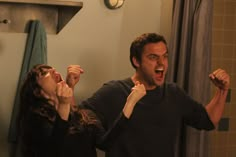 a man and woman standing in front of a mirror brushing their teeth with toothbrushes