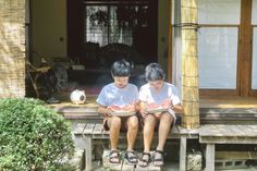 two young boys sitting on a porch with watermelon slices in front of them