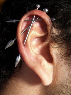 there is a man with three different piercings on his ear and one behind the ear