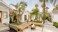 a fire pit sitting in the middle of a yard next to palm trees and buildings