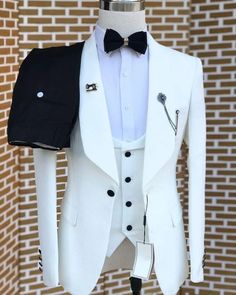 a white tuxedo with black lapel collar and bow tie on display in front of a brick wall