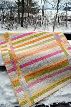 a quilted blanket sitting on top of snow covered ground