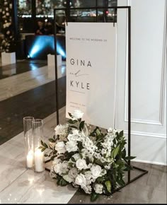 flowers and candles sit on the floor next to a sign that reads, welcome to the wedding of gina kyle