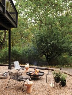 a fire pit surrounded by chairs and tables in the middle of a graveled area