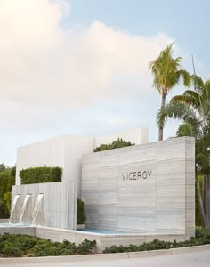 a large building with a fountain in front of it and palm trees around the entrance