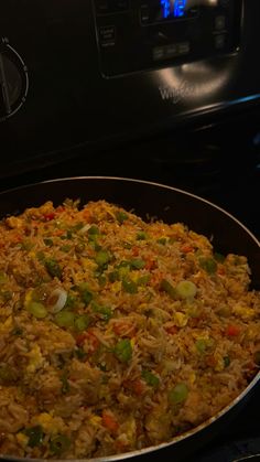 a pan filled with rice and vegetables on top of an oven burner next to the stove