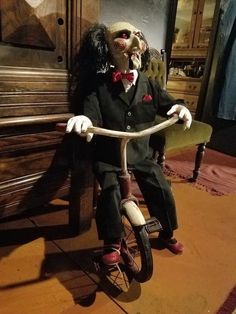 a creepy clown riding a tricycle on the floor