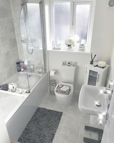 a bathroom with a toilet, sink and bathtub next to a window in it