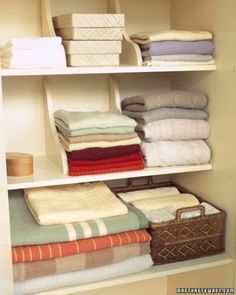 an organized closet with folded towels and baskets on the shelves in front of each other