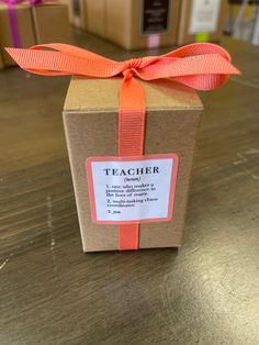 a brown box with an orange ribbon on top of a wooden table next to other boxes