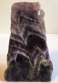 a piece of rock that has some kind of purple substance on top of it and is sitting on a white surface