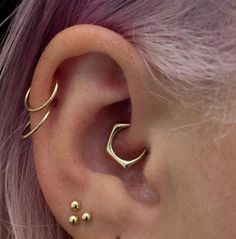 a woman with pink hair wearing gold ear piercings